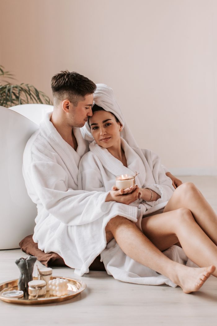 A loving couple in bathrobes enjoying a relaxing moment indoors with candles.